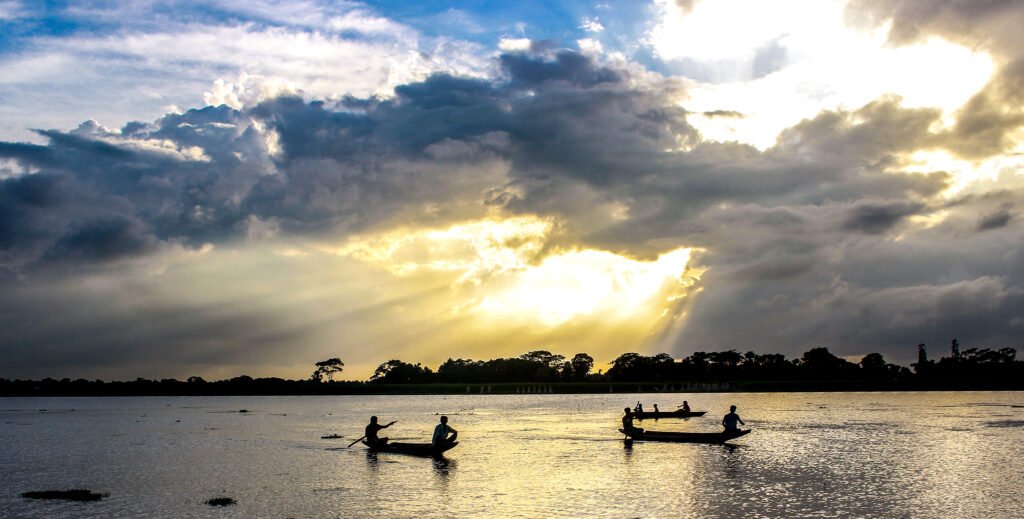 Sunlight over a river with distant boat silhouettes